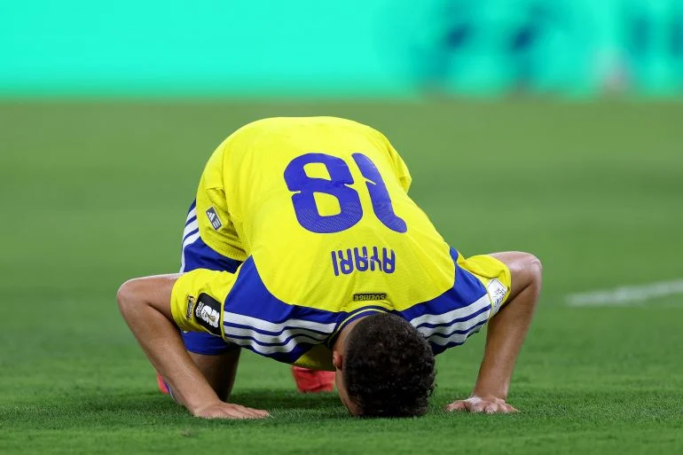 Ayari went down on the ground to prostrate after scoring his first World Cup goal [Julio Cesar Aguilar/AFP]